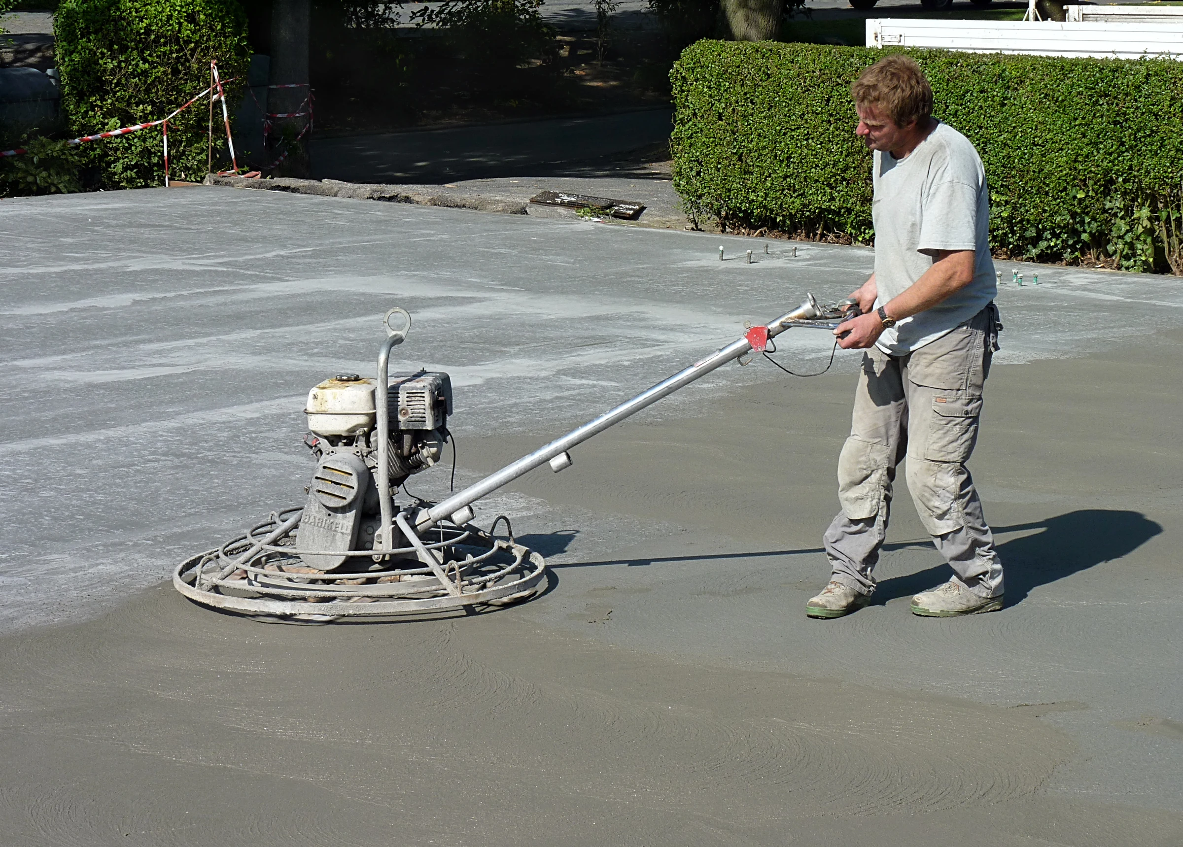 Worker finishing a freshly poured concrete slab with a power trowel