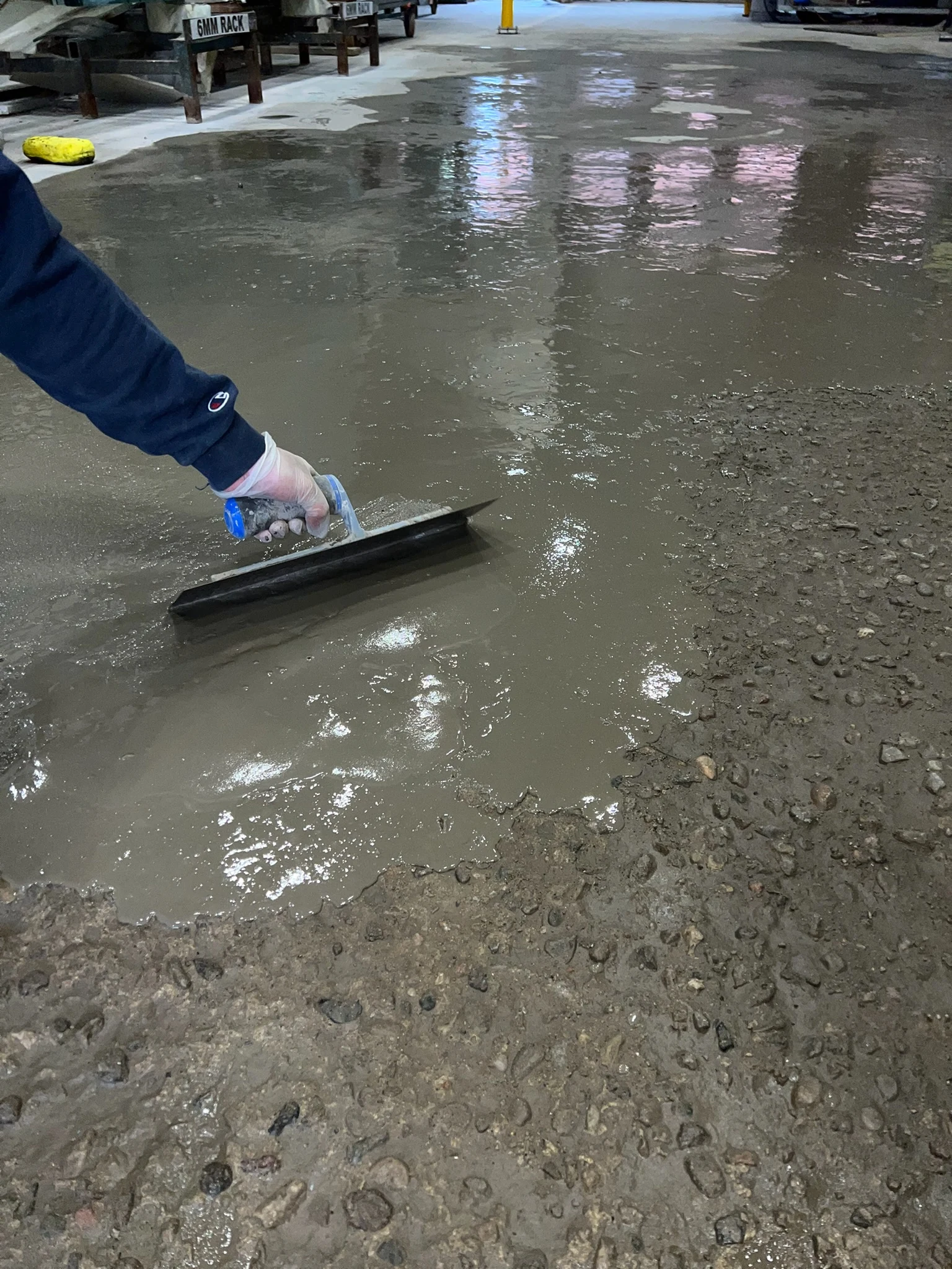 Self-levelling cement spread with a trowel over a ground concrete slab